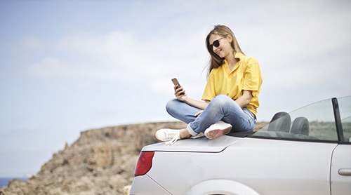 Woman texting above her car